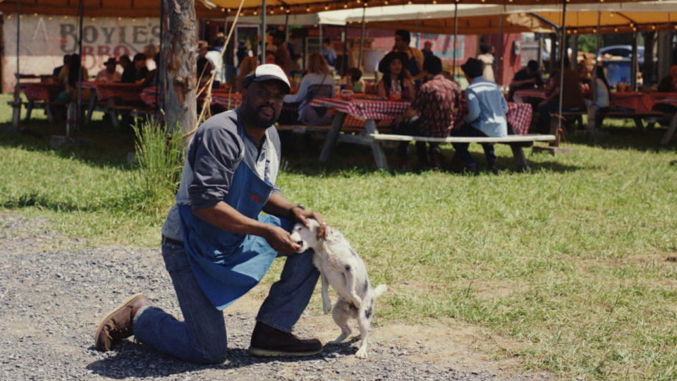 Larry Brown kneels down to make friends with a dog in Poker Face.