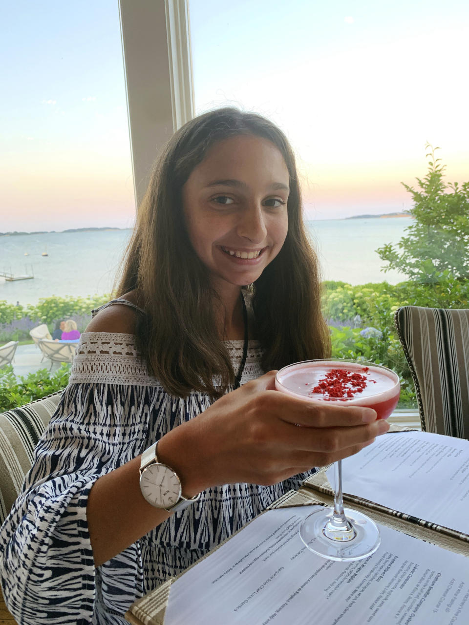 This July 1, 2019 photo shows Lauren Minichiello, 11, holds a Rose Martini mocktail at a restaurant at Wequassett Resort and Golf Club in Harwich, Mass. (Erin minichiello via AP)