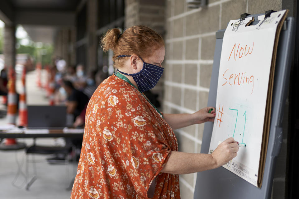 FILE - In this July 15, 2020, file photo, one-stop operator Vickie Gregorio with the Heartland Workforce Solutions updates a whiteboard outside the workforce office in Omaha, Neb., as those seeking employment await their turn outside. The Labor Department reported unemployment numbers Thursday, Sept. 3. (AP Photo/Nati Harnik, File)