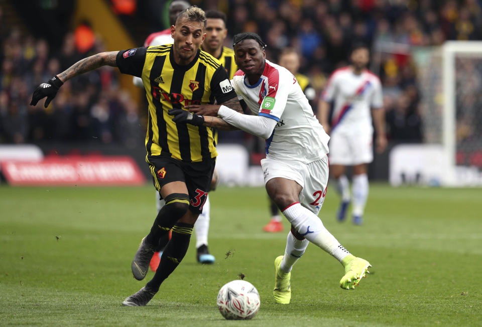 Watford's Roberto Pereyra, left and Crystal Palace's Aaron Wan-Bissaka battle for the ball , during the FA Cup quarter final soccer match between Watford and Crystal Palace , at Vicarage Road, in Watford, England, Saturday March 16, 2019. (Jonathan Brady/PA via AP)