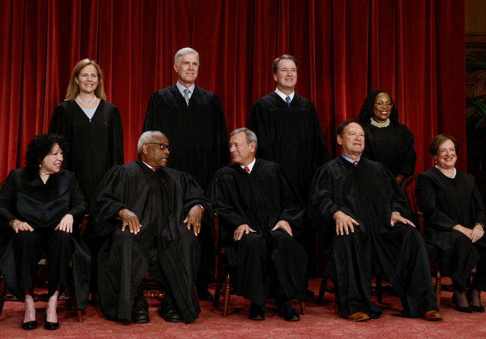 Five Supreme Court justices sit and four stand behind them as they gather for a group portrait.