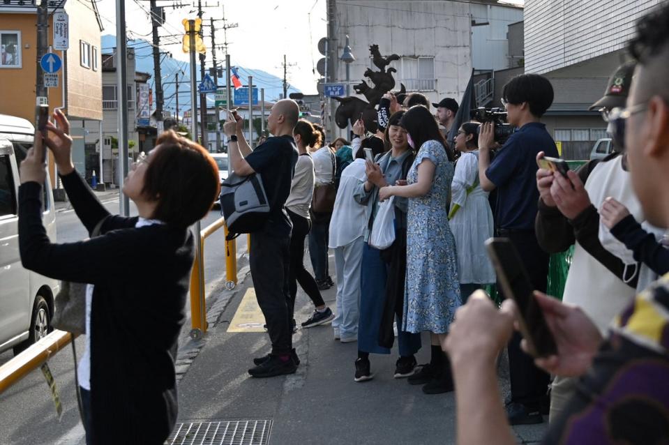 Tourists crowding the pavement to take pictures of Mount Fuji from opposite a convenience store in the town of Fujikawaguchiko (Getty)