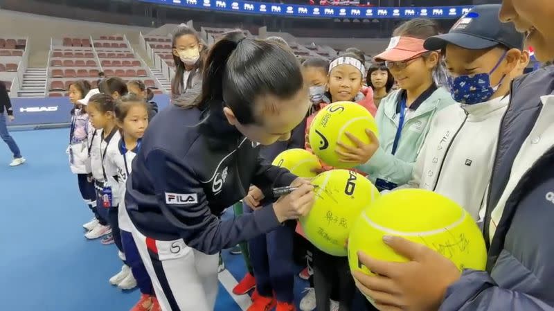 Chinese tennis player Peng Shuai signs large-sized tennis balls at the opening ceremony of Fila Kids Junior Tennis Challenger Final in Beijing