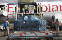 FILE - Airport workers spray the cargo of COVID-19 vaccines, donated through the U.N.-backed COVAX program, on arrival in Antananarivo, Madagascar, May 8, 2021. COVAX, created to share coronavirus vaccines fairly, already scaled back its pledge to the world's poor once. Now, to meet even that limited promise, it would have to deliver more than a million doses every hour until the end of the year. (AP Photo/Alexander Joe, File)