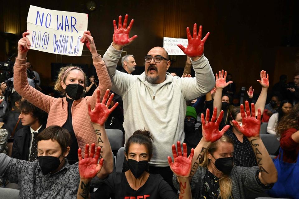 Protesters raise their painted hands as US Secretary of State Antony Blinken and Defense Secretary Lloyd Austin testify during a Senate Appropriations Committee hearing to examine the national security supplemental request (AFP via Getty Images)