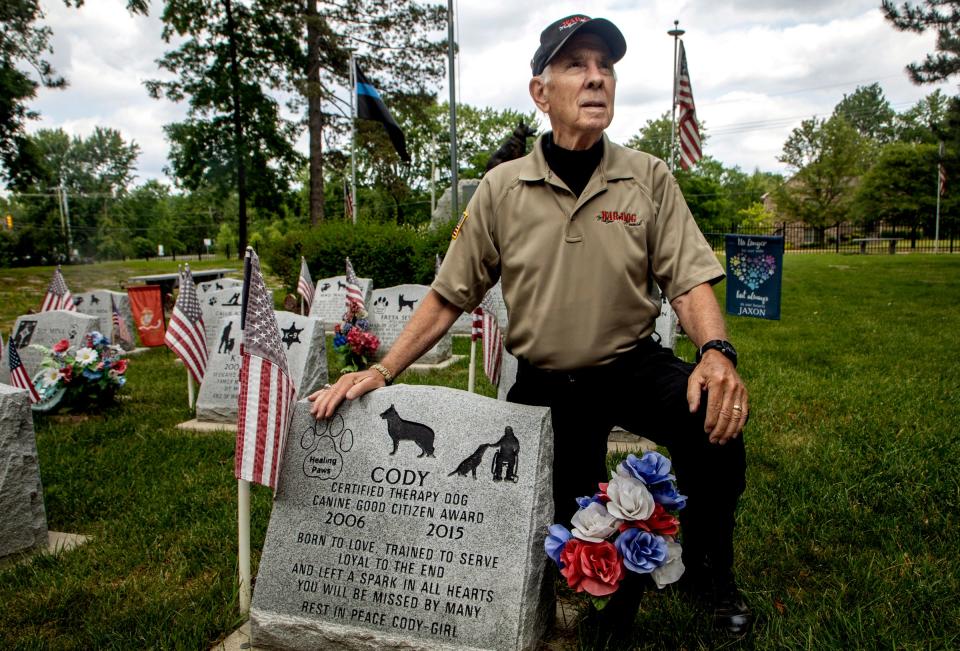 Phil Weitlauf, director of Michigan War Dog Memorial, Inc., kneels next to the gravestone of his dog Cody that was buried inside the Michigan War Dog Memorial in South Lyon on June 14, 2023.