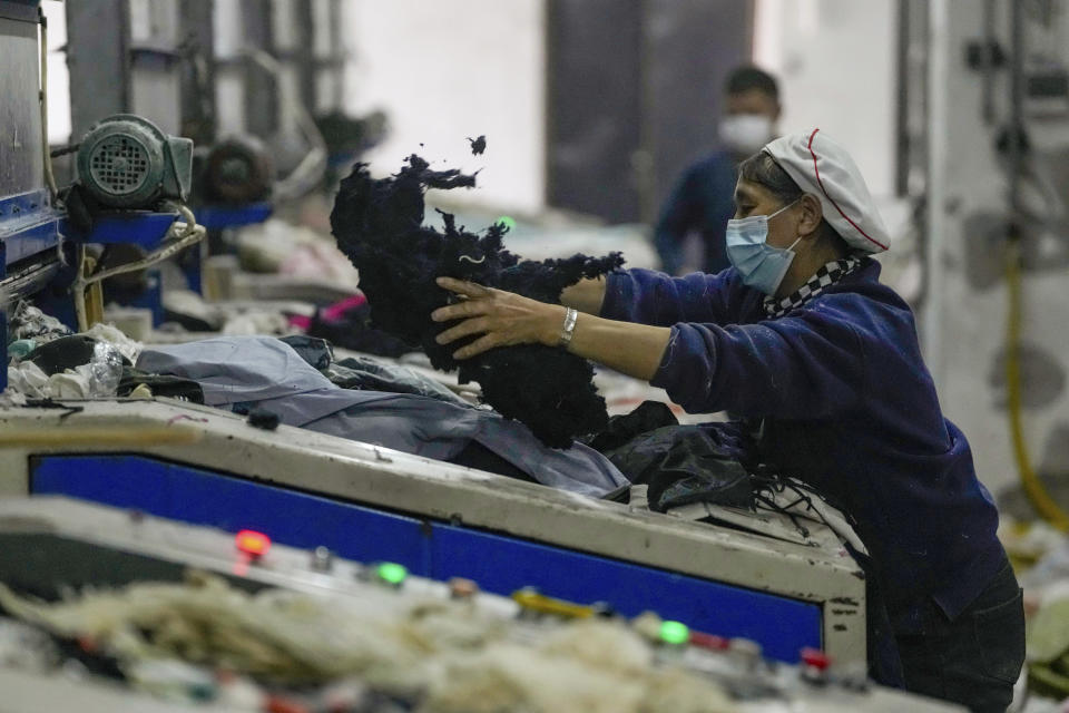 A worker feeds discarded textiles to a shredding machine at the Wenzhou Tiancheng Textile Company, one of China's largest cotton recycling plants in Wenzhou in eastern China's Zhejiang province on March 20, 2024. (AP Photo/Ng Han Guan)
