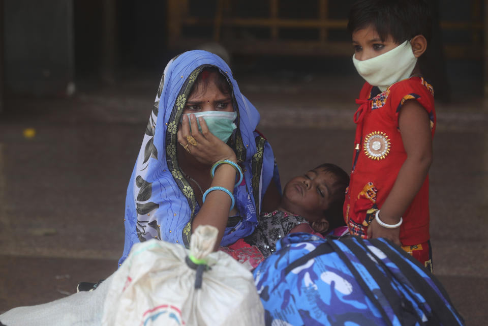 A woman along with her children wait for a train at Lokmanya Tilak Terminus in Mumbai, India, Wednesday, April 7, 2021. India hits another new peak with 115,736 coronavirus cases reported in the past 24 hours with New Delhi, Mumbai and dozens of other cities imposing night curfews to check the soaring infections. (AP Photo/Rafiq Maqbool)