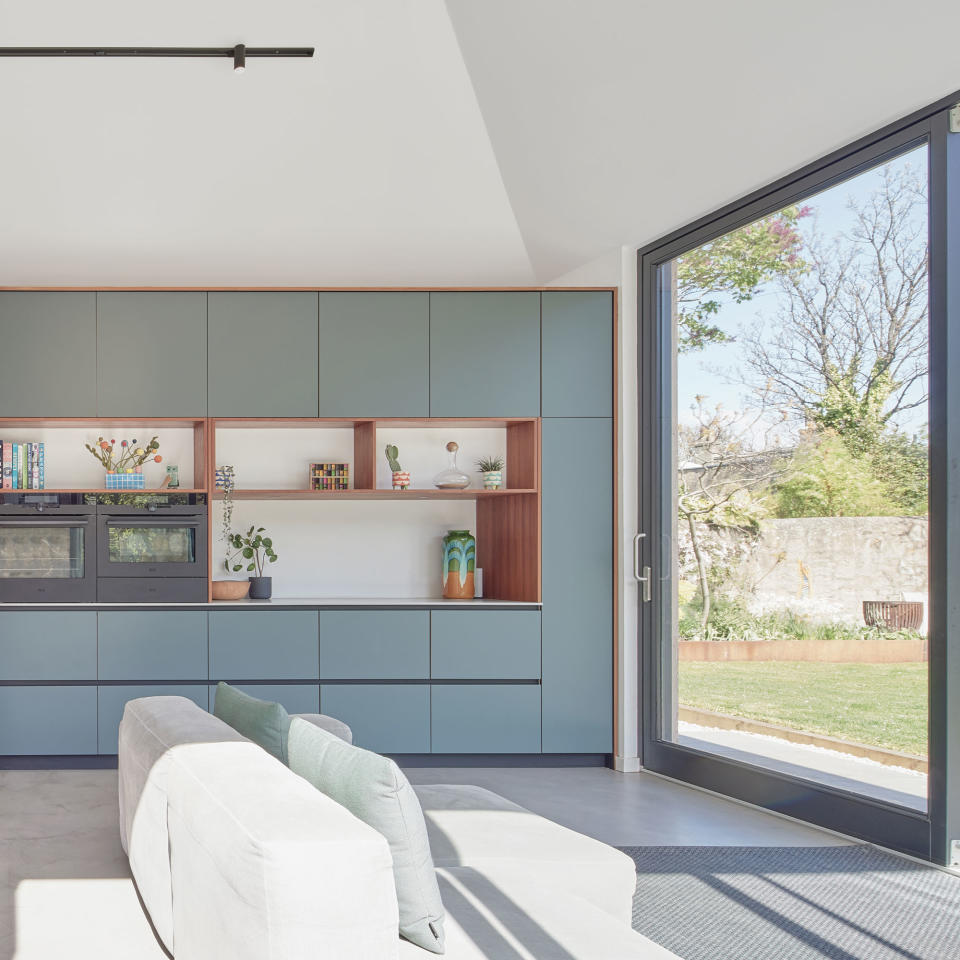 a pale blue plywood kitchen with and floor to ceiling patio doors