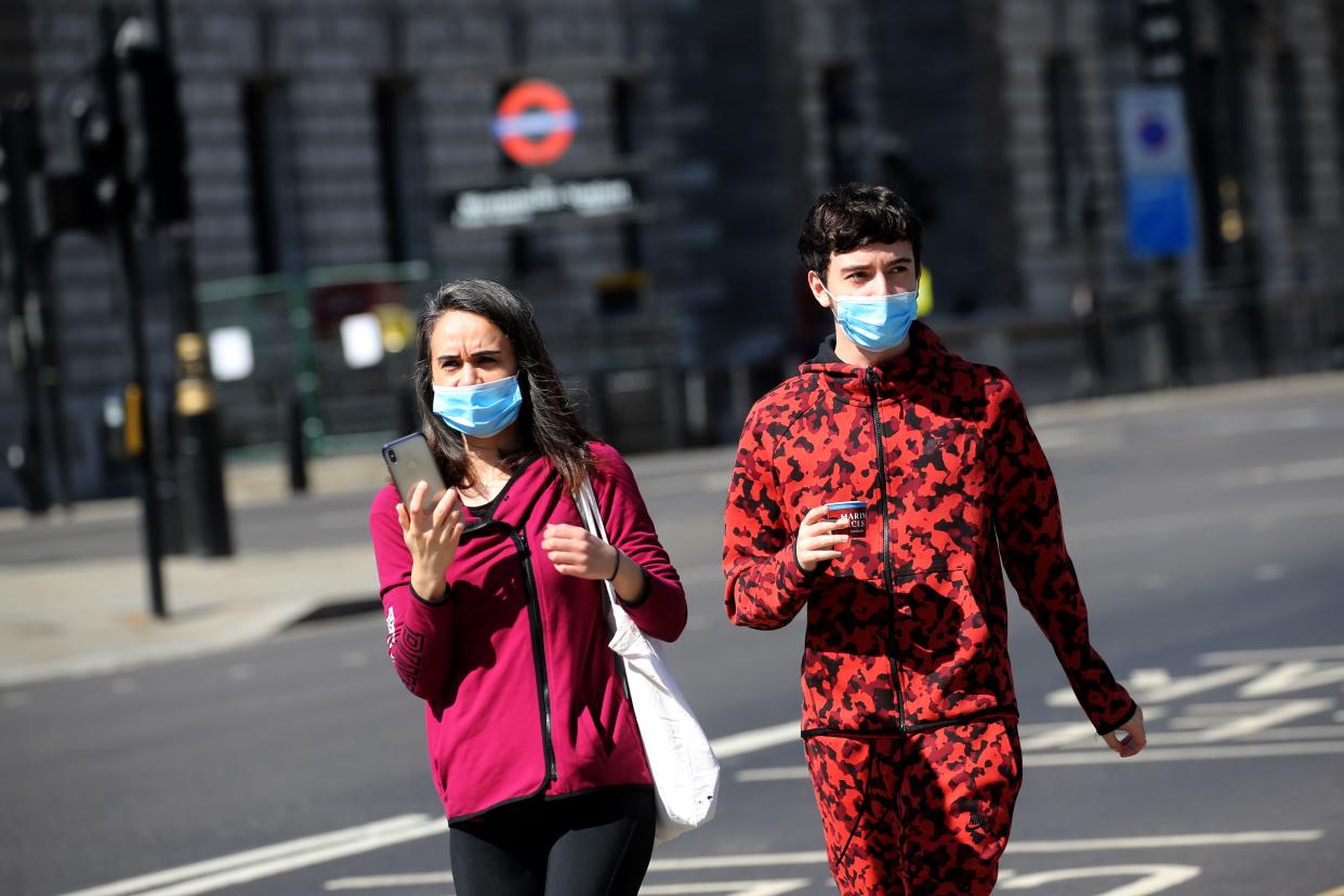 A couple wear facemasks as they walk near the Houses of Parliament in Westminster, central London on April 21, 2020, during the nationwide lockdown to combat the novel coronavirus COVID-19 pandemic. - The British parliament returns on Tuesday from an extended Easter break, allowing lawmakers to scrutinise ministers as criticism grows of government handling of the coronavirus crisis and deaths outside hospitals increase. (Photo by Isabel Infantes / AFP) (Photo by ISABEL INFANTES/AFP via Getty Images)