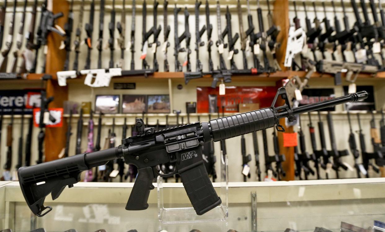 In this Thursday, March 1, 2018, photo a Smith & Wesson M&P; 15 Sport rifle chambered in 5.56 mm is shown in front of a rack of other rifles at Duke's Sport Shop in New Castle, Pa. 