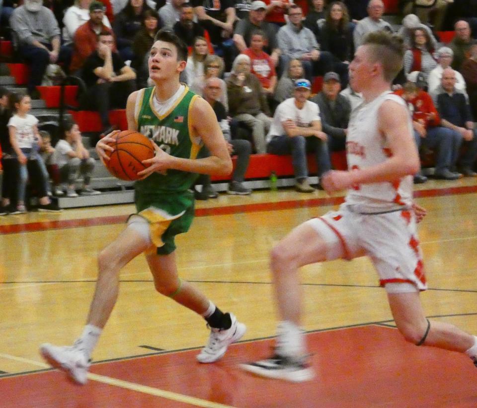 Newark Catholic senior Ashton Cox gathers to go up for a transition layup with Utica sophomore Roman Gamble in pursuit on Friday, Jan. 28, 2022. Cox scored 12 points to help the visiting Green Wave earn a 70-66 victory.