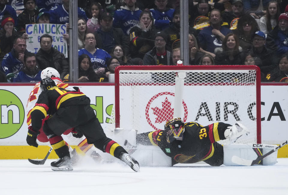 Vancouver Canucks goalie Thatcher Demko, right, stops Calgary Flames' Nazem Kadri, back left, during overtime in an NHL hockey game Saturday, April 8, 2023, in Vancouver, British Columbia. (Darryl Dyck/The Canadian Press via AP)