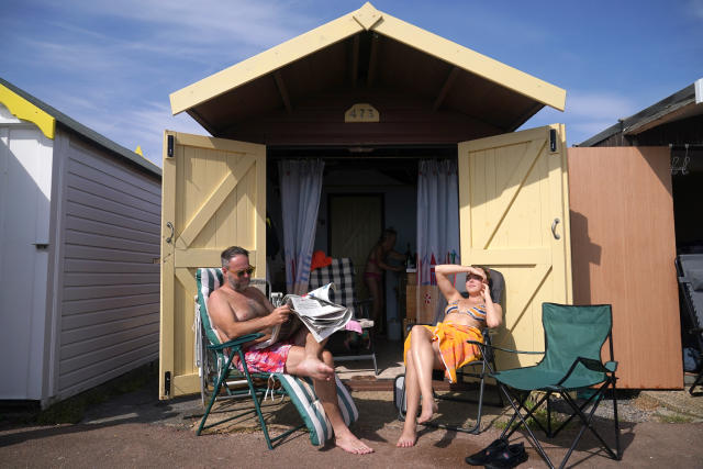 People sit outside a beach hut at Thorpe Bay, Southend-on-Sea on the Thames Estuary in Essex. Temperatures are predicted to hit 31C across central England on Sunday ahead of record-breaking highs next week. Picture date: Sunday July 17, 2022.