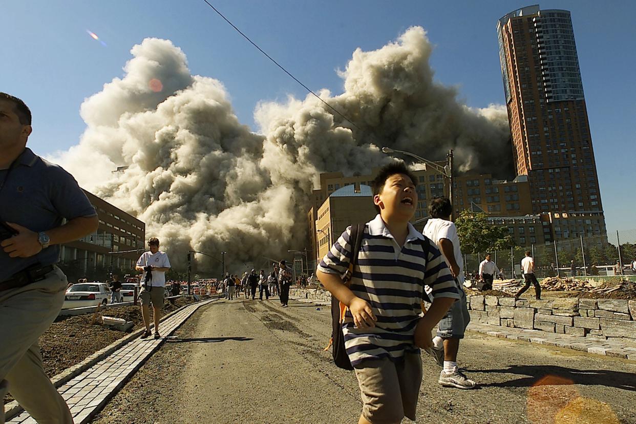 People run away as the second tower of World Trade Center crumbles down after a plane hit the building September 11, 2001, in New York City.