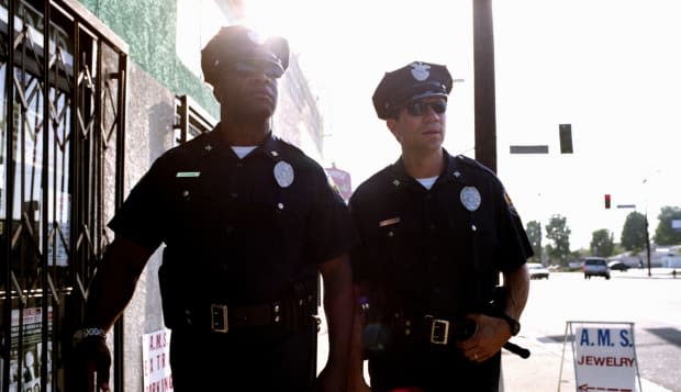 Two policemen wearing sungalsses, walking down sidewalk