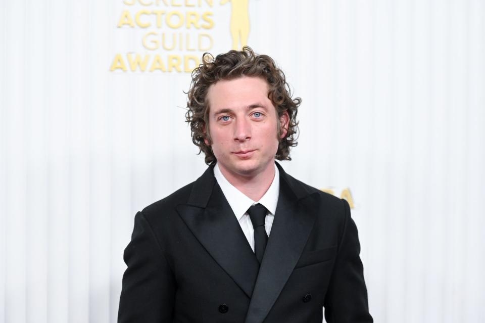 jeremy allen white posing on the red carpet in a black suit
