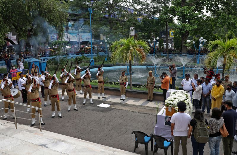 Policemen offer a gun salute next to the coffin containing the body of Indian singer KK in Kolkata