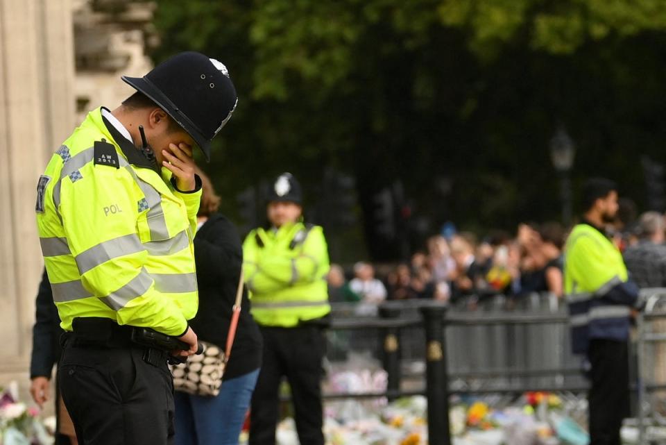 A police officer reacts as he stands guard in front of Buckingham Palace, (REUTERS)