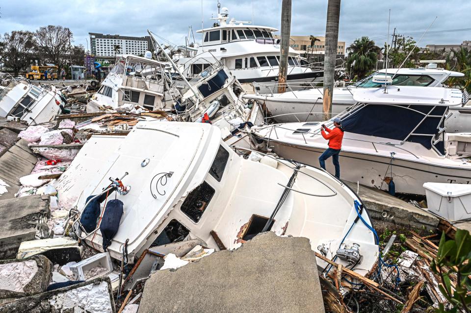 A man takes photos of boats damaged by Hurricane Ian in Fort Myers, Fla., on Sept.29, 2022.