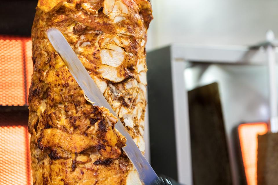 Chicken is cut from a vertical spit in the kitchen at Supreme Shawarma in Chandler on Feb. 17, 2022.