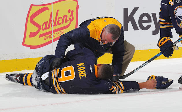 BUFFALO, NY - OCTOBER 13: Evander Kane #9 of the Buffao Sabres is tended to by head athletic trainer Rich Stinziano after crashing into the boards during an NHL game at the KeyBank Center on October 13, 2016 in Buffalo, New York. (Photo by Bill Wippert/NHLI via Getty Images)