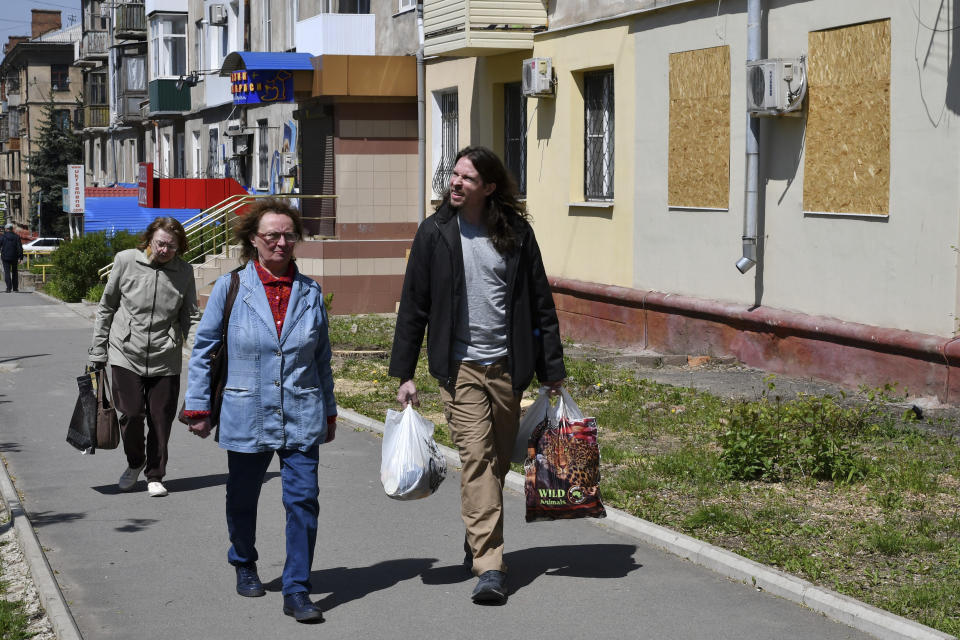 Patrick Michael Jones, 34, a volunteer from Houston, U.S. helps Ukrainian women Vera, 59, centre, and Lilia, 55, to carry humanitarian aid in Kramatorsk, Ukraine, Friday, May 6, 2022. Jones came to Ukraine to help people in their difficult situation. He worked as a salesman at a gun store in Houston. (AP Photo/Andriy Andriyenko)