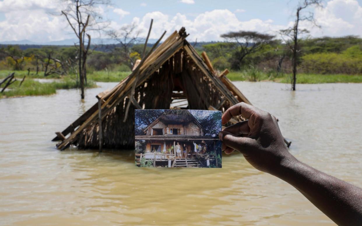 Camp manager James Owuor, holds a photo showing a structure before it was submerged under rising water due to months of unusually heavy rains, in lake Baringo, Kenya.  - BAZ RATNER /Reuters