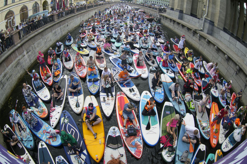 People steer their stand-up paddle (SUP) boards along the Griboedov Channel during the annual costumed 'Fontanka' SUP-boards festival in St. Petersburg, Russia, Saturday, Aug. 5, 2023. (AP Photo/Dmitri Lovetsky)