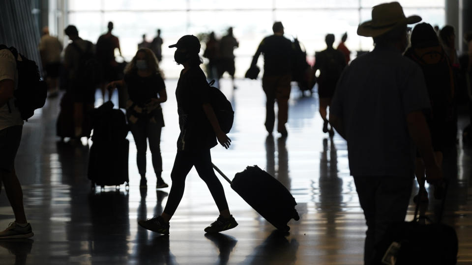 FILE - In this July 1, 2021, file photo, people travel through Salt Lake City International Airport in Salt Lake City. Americans enjoying newfound liberty are expected to travel and gather for cookouts, fireworks and family reunions over the Fourth of July weekend in numbers not seen since pre-pandemic days. (AP Photo/Rick Bowmer, File)