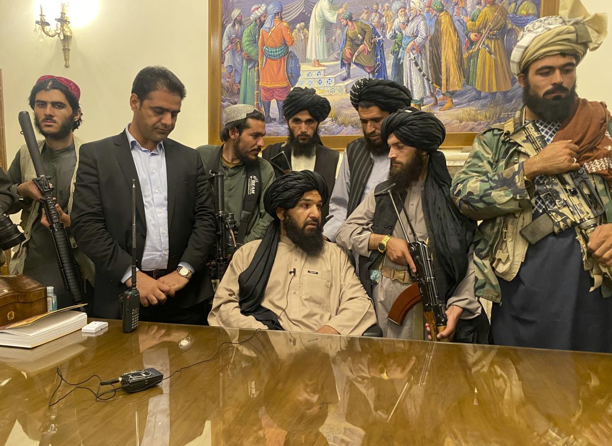 Taliban fighters take control of the Afghan presidential palace after Afghan President Ashraf Ghani fled the country, in Kabul, Afghanistan on Sunday, Aug. 15, 2021. The person second from left is a former bodyguard for Ghani.