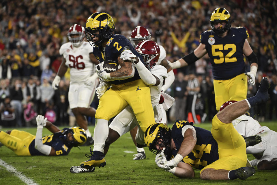 Michigan running back Blake Corum (2) runs in for a touchdown past Alabama defensive back Kool-Aid McKinstry (1) during overtime at the Rose Bowl CFP NCAA semifinal college football game Monday, Jan. 1, 2024, in Pasadena, Calif. (AP Photo/Kyusung Gong)