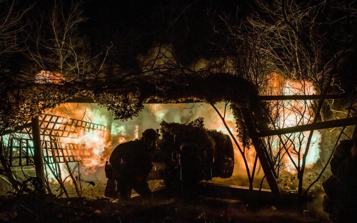 Ukrainian servicemen operate a D-30 artillery canon late at night