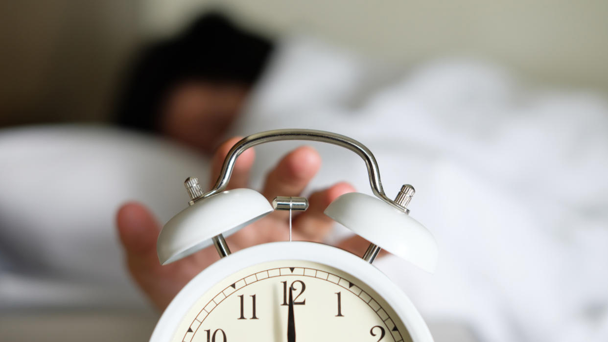  woman turning off an alarm clock 