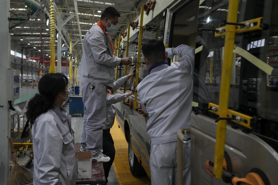 FILE - Workers install window panels on a minibus at a factory during a media organized tour in Shiyan city in central China's Hubei Province on May 10, 2023. A survey Wednesday, May 31, 2023 showed China's factory activity decelerated in May, adding to signs its economic rebound after the end of anti-virus controls is slowing. (AP Photo/Andy Wong, File)