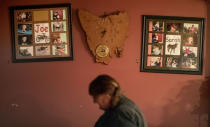 Carmall Casey walks past photos of her kids that hang next to a clock in the shape of Tasmania, in her home in Black River, Tasmania, Australia, Tuesday, July 23, 2019. While struggling with her addiction, Casey lost her farm. Even worse, she says, she lost her daughter. She made bad choices on the drugs, she admits now. She was living with a volatile man who began to bully Sarah, so she sent her daughter, then 14, to live with her father. It's a decision that tore them apart, and still tears Casey apart today. (AP Photo/David Goldman)