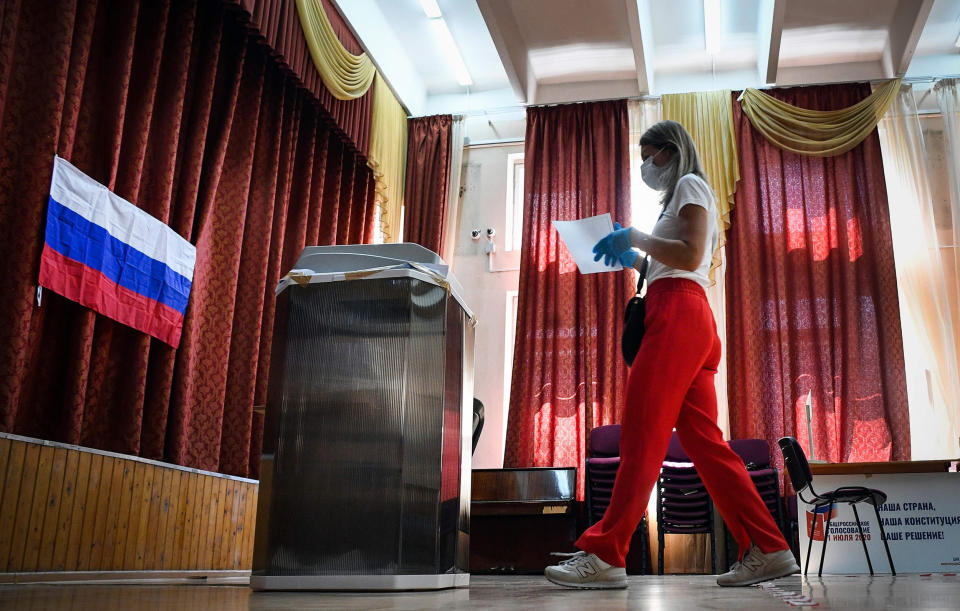 Image: A woman wearing a face mask and gloves walks to cast her ballot in a nationwide vote on constitutional reforms at a polling station in Moscow (Alexander Nemenov / AFP - Getty Images)