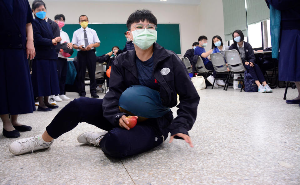 學生在腰上綁上氣球後，還需完成撿蘋果任務，不慎跌坐地板。