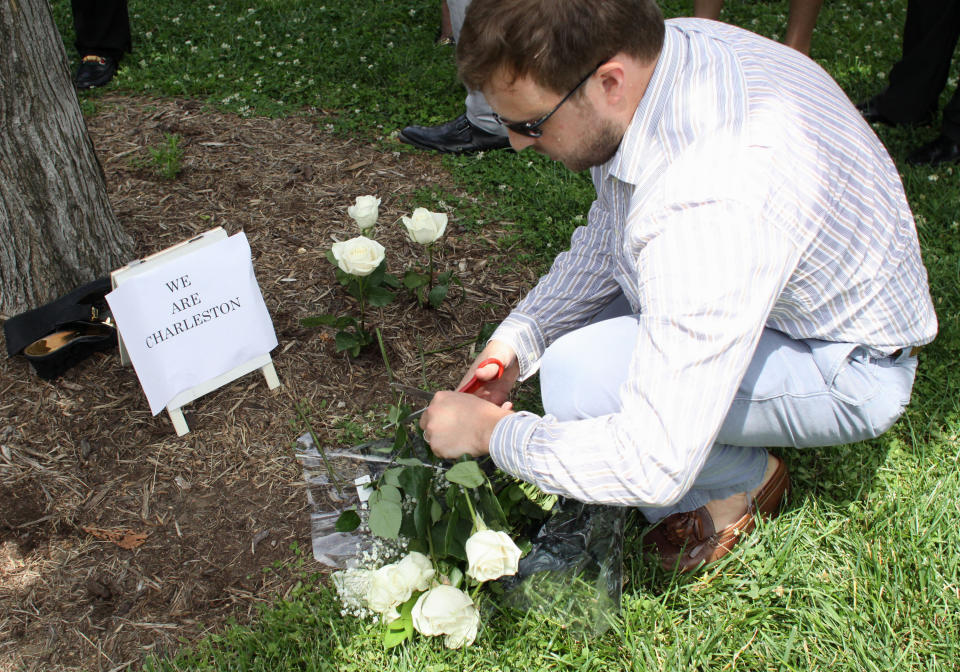 Travis Norton, a staffer in the office of Sen. Tim Scott, R-S.C., plants nine roses on the lawn on Capitol Hill in Washington, Thursday, June 18, 2015, as members of Congress and staff gather in prayer  to mourn the shooting victims of Emanuel AME Church in Charleston, S.C. (AP Photo/Lauren Victoria Burke)