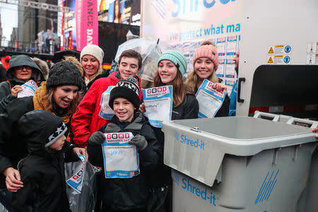 People participate in the National Good Riddance day ceremonial shredding of bad memories of 2018 in Times Square in the Manhattan borough of New York, U.S., December 28, 2018. REUTERS/Jeenah Moon