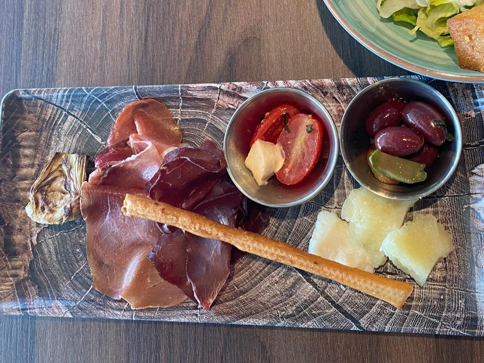 charcuterie board and a salad on a table at a restaurant on a disney cruise ship