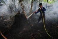 A Pontianak city fire fighter sprays water on a peat land fire on the outsikirts of Pontianak, West Kalimantan, Indonesia August 22, 2016. Antara Foto/Jessica Helena Wuysang/ via REUTERS