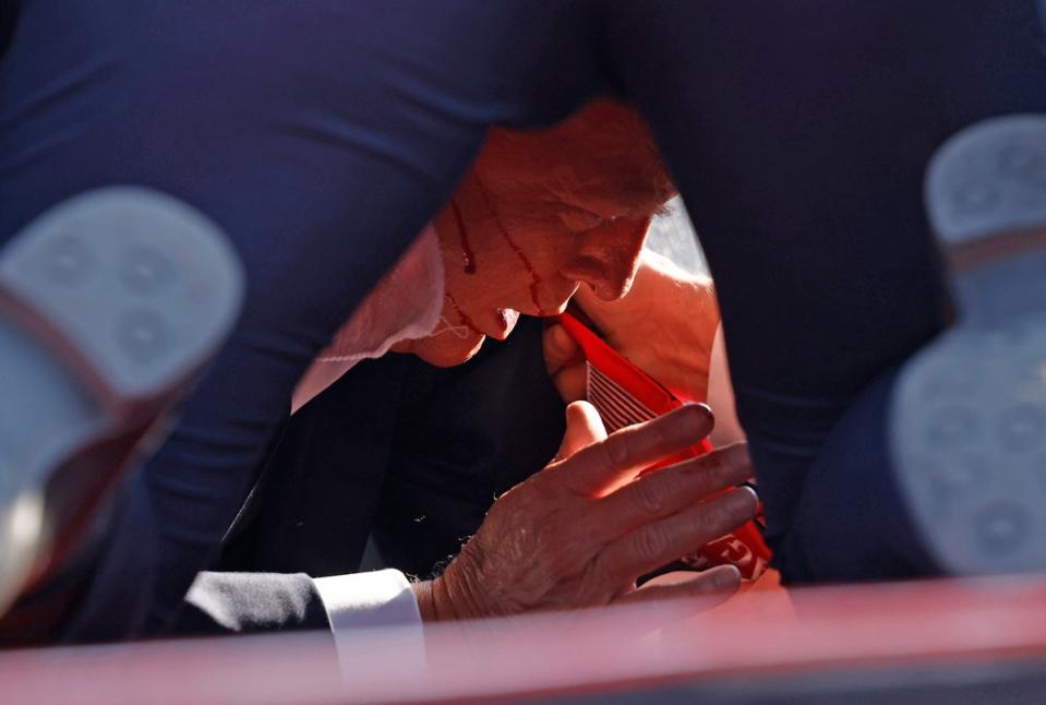 Trump was rushed to the floor by secret service agents and was later seen with blood trickling down his face (Getty Images)