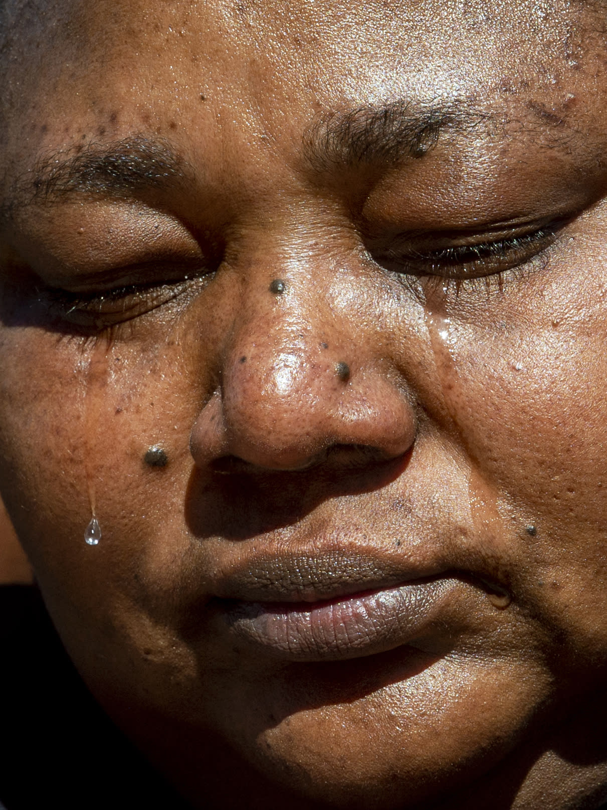 Tears flow as Dorcas Lyoya, mother of Patrick Lyoya, sits somberly after marching with more supporters wearing all black on Thursday, April 21, 2022 as speakers begin to talk about her son on the steps of the Michigan Capitol in Lansing, Mich. to demand justice in the police shooting that took the life of Congolese immigrant Patrick Lyoya. (Jake May/The Flint Journal via AP)