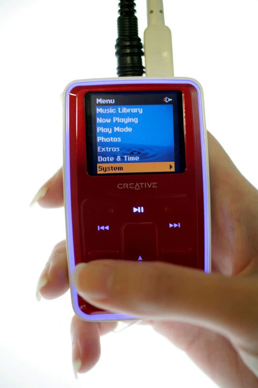 FILE PHOTO: A staff poses with a Creative MP3 player in Singapore May 17, 2006. MP3 music player maker Creative'..