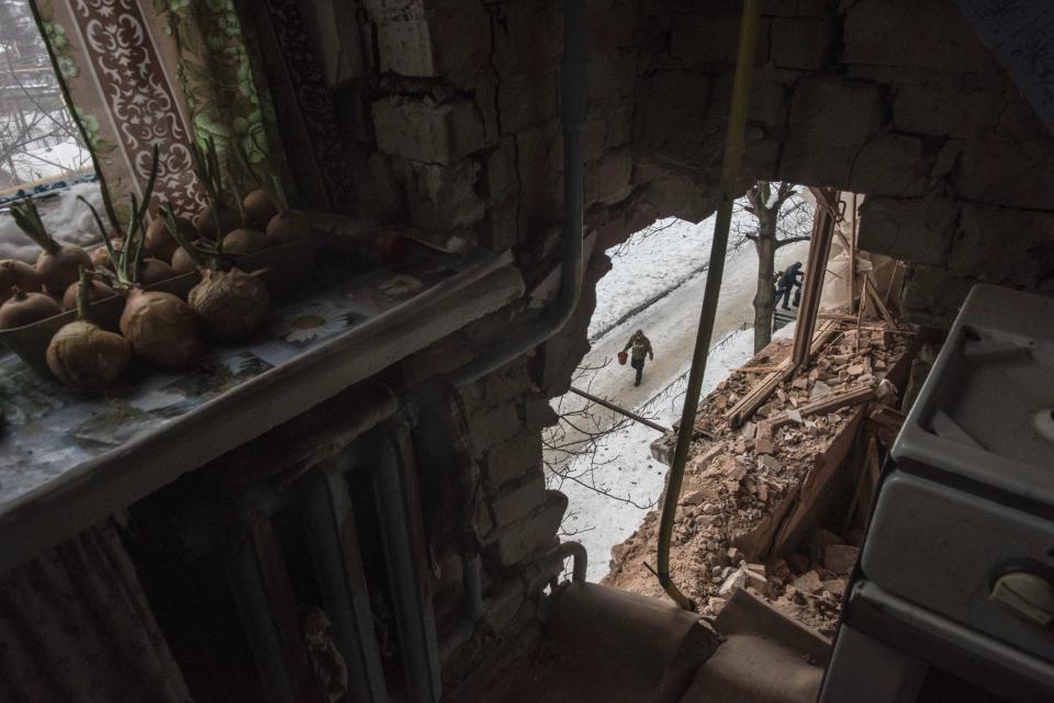 A local resident walking in a street is seen through a hole in an apartment building damaged by shelling in Avdiivka, Ukraine, Saturday, Feb. 4, 2017. Fighting in eastern Ukraine sharply escalated this week. The Ukrainian command said Saturday that several soldiers were killed in the past day. (AP Photo/Evgeniy Maloletka)