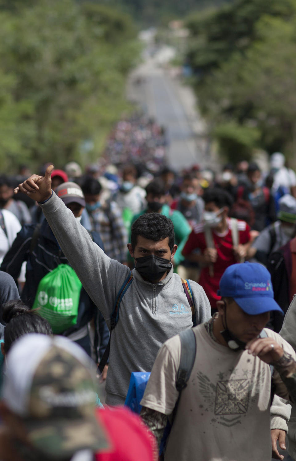 A Honduran migrant gives a thumbs-up as he walks with other migrants in hopes of reaching the U.S. border, in Chiquimula, Guatemala, Saturday, Jan. 16, 2021. Guatemalan authorities estimated that as many as 9,000 Honduran migrants crossed into Guatemala as part of an effort to form a new caravan to reach the U.S. border. (AP Photo/Sandra Sebastian)