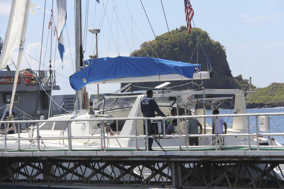 Investigators from Grenada and St. Vincent and the Grenadines stand aboard the yacht "Simplicity", that they say was hijacked by 3 escaped prisoners with two people aboard, now anchored at the St. Vincent and the Grenadines Coastguard Service Calliaqua Base, in Calliaqua, St. Vincent, Friday, Feb. 23, 2024. Authorities in the eastern Caribbean said they were trying to locate two people believed to be U.S. citizens who were aboard the yacht that was hijacked by the three escaped prisoners from Grenada. (AP Photo/Kenton X. Chance)