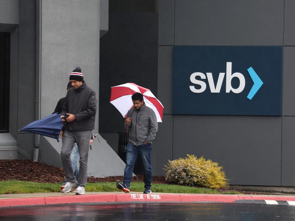 People walk in the rain with an umbrella outside Silicon Valley Bank