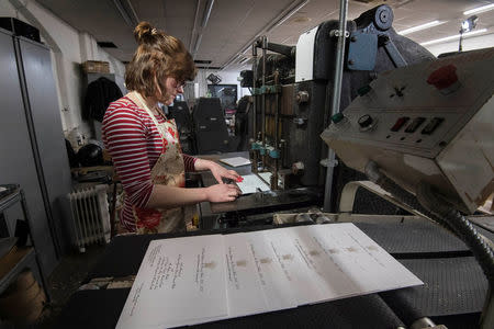 Lottie Small use the die stamping press at the workshop of Barnard and Westwood, who are printing the invitations for Britain's Prince Harry and Meghan Markle's wedding at Windsor Castle in May, London, Britain, March 22, 2018. Victoria Jones/Pool via Reuters